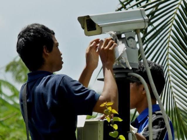 Teknisi berpengalaman memasang kamera CCTV IP di kawasan industri Cikarang Bekasi menggunakan helm keselamatan