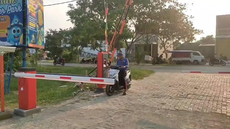 Palang parkir otomatis aktif — kendaraan melintas melalui sistem gate kawasan parkir industri